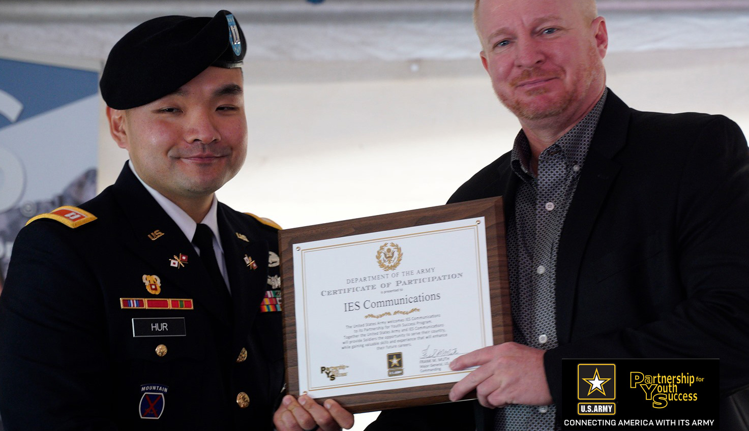 Ĵý Communications executive receives a certificate from a US Army official for participation in the US Army Partnership for Youth Success program